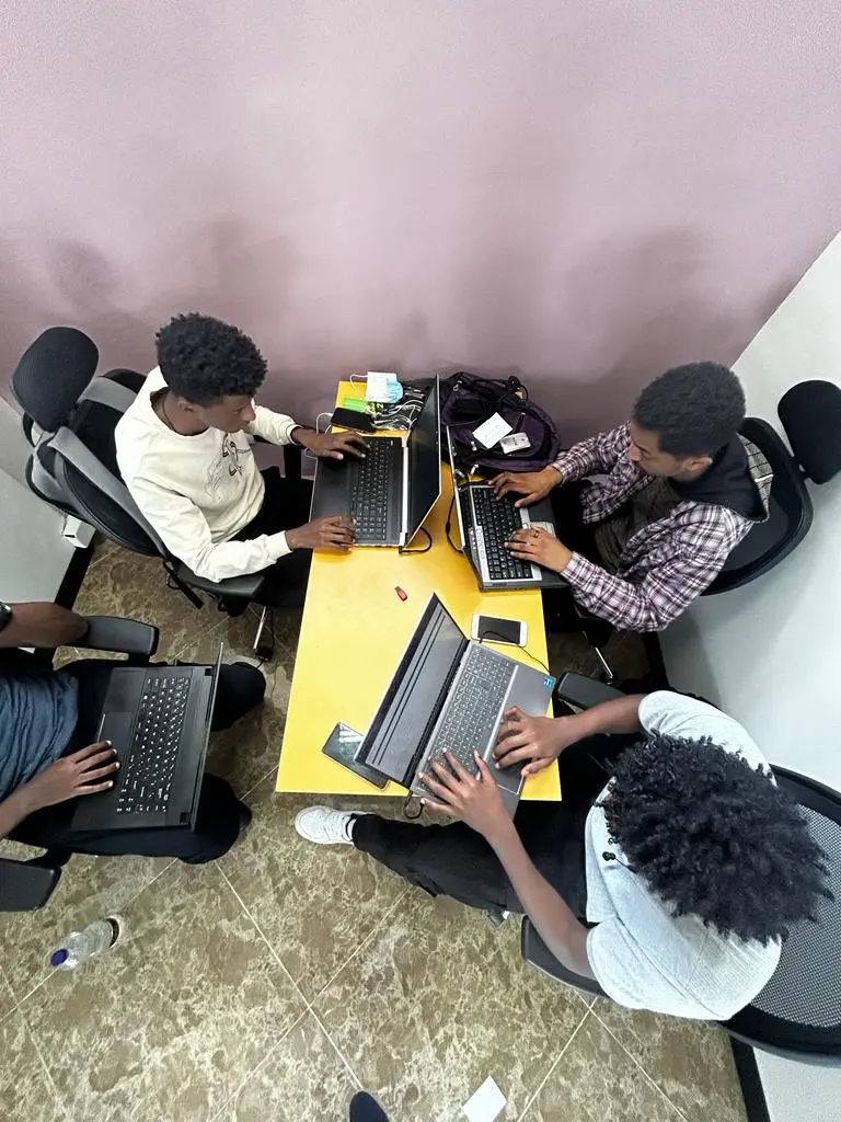 Overhead view of a CyberShield team collaborating around laptops in 2023